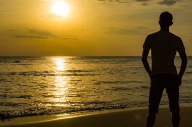 Golden sunset plajında genç adam silüeti