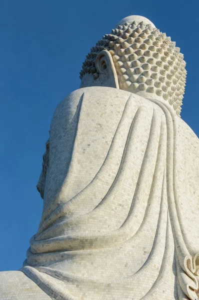 Back view of the white marble statue of Big Buddha on blue sky background