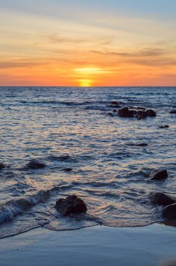 Gündoğumu veya günbatımı turuncu gökyüzü ile tropikal plaj deniz manzarası üzerinde