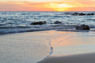 Gündoğumu veya günbatımı turuncu gökyüzü ile tropikal plaj deniz manzarası üzerinde