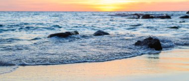 Gündoğumu veya günbatımı turuncu gökyüzü ile tropikal plaj deniz manzarası üzerinde