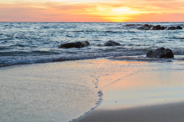 Gündoğumu veya günbatımı turuncu gökyüzü ile tropikal plaj deniz manzarası üzerinde