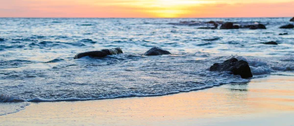 Gündoğumu veya günbatımı turuncu gökyüzü ile tropikal plaj deniz manzarası üzerinde