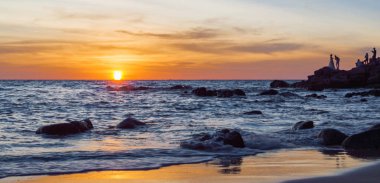 Gündoğumu veya günbatımı turuncu gökyüzü ile tropikal plaj deniz manzarası üzerinde