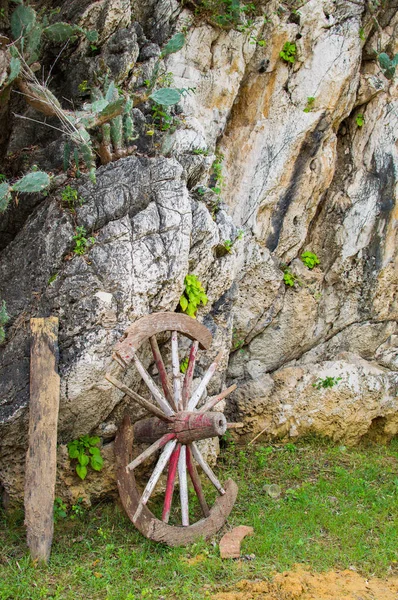 Une vieille roue de chariot en bois brisé appuyé contre un mur de pierre — Photo