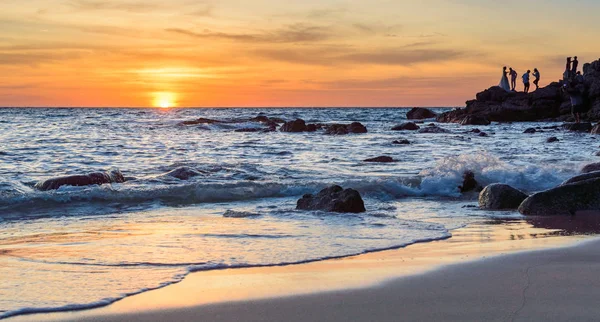 Gündoğumu veya günbatımı turuncu gökyüzü ile tropikal plaj deniz manzarası üzerinde