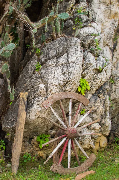 Une vieille roue de chariot en bois brisé appuyé contre un mur de pierre — Photo