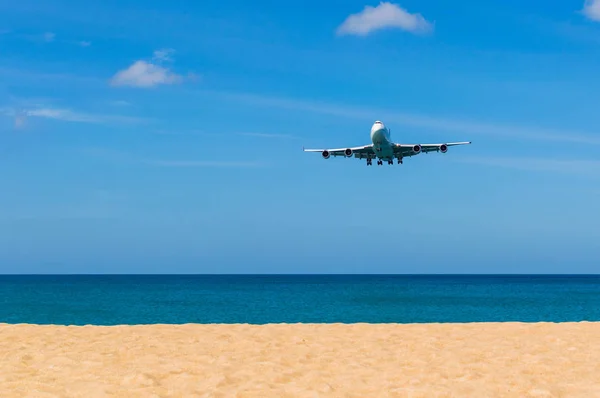Airplane landing above beautiful beach and sea background — Stock Photo, Image