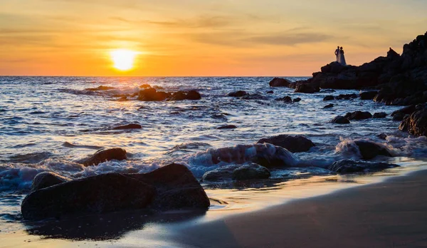 Gündoğumu veya günbatımı turuncu gökyüzü ile tropikal plaj deniz manzarası üzerinde