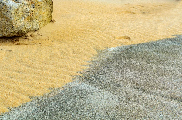 Sable d'une mer peu profonde dans les vagues de lumière sur la surface de la pierre, fond de la nature . — Photo