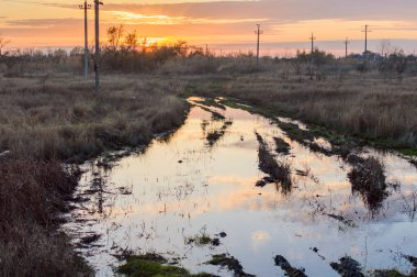 Azıyorum Rus alanındaki bir toprak yol üzerinde batan güneşin yansıması