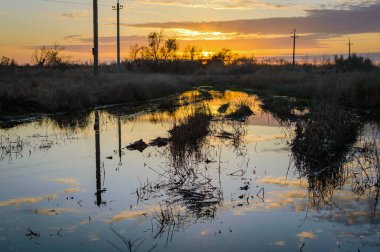 Azıyorum Rus alanındaki bir toprak yol üzerinde batan güneşin yansıması
