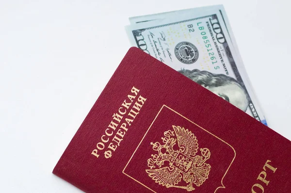 Duas notas de 100 dólares americanos cada, deitadas no passaporte russo num fundo branco. — Fotografia de Stock