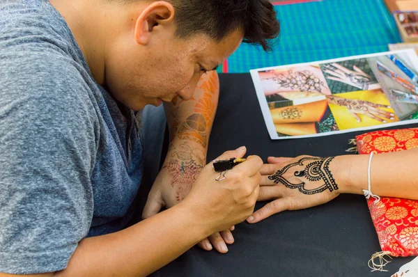 Tailândia, Phuket, 03 de fevereiro de 2017: Artista asiático mehendi. Um homem bonito desenhando mehendi na mão . — Fotografia de Stock