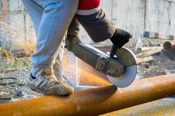 Mannenhand afsnijdt van stukken waterleiding met haakse slijper — Stockfoto