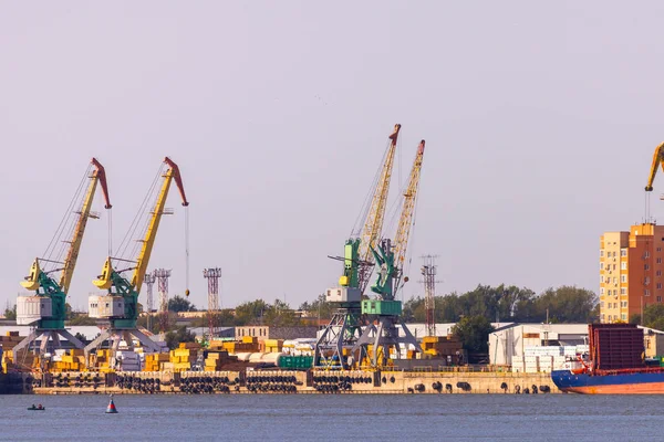 Промышленный ландшафт с портовыми кранами в порту на фоне городского пейзажа — стоковое фото