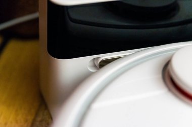 Beyaz robot elektrikli süpürgenin şarj istasyonunun bağlantıları üste şarj oluyor. Modern akıllı elektronik temizlik teknolojisi..