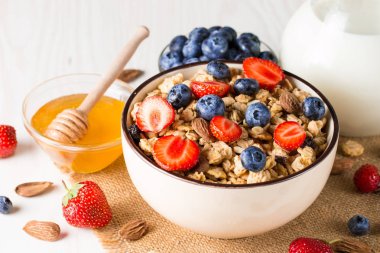 Sağlıklı kahvaltı konsepti ile yulaf gevreği ve rustik arka plan üzerinde taze çilek. Granola yapılan yemekleri müsli. Böğürtlen, muslie, çilek, yaban mersini ve bal ile sağlıklı muz smoothie.