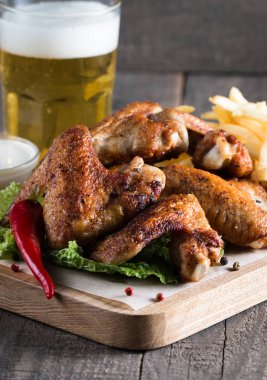 Yakın çekim fotoğraf Barbekü tavuk kanatlı patates ve bira. Barbekü soslar, ketçap, mayonez etli. Hızlı ve abur cubur kavramı. 