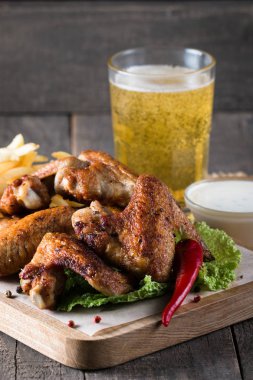 Yakın çekim fotoğraf Barbekü tavuk kanatlı patates ve bira. Barbekü soslar, ketçap, mayonez etli. Hızlı ve abur cubur kavramı. 