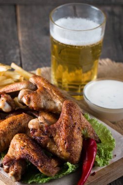 Yakın çekim fotoğraf Barbekü tavuk kanatlı patates ve bira. Barbekü soslar, ketçap, mayonez etli. Hızlı ve abur cubur kavramı. 