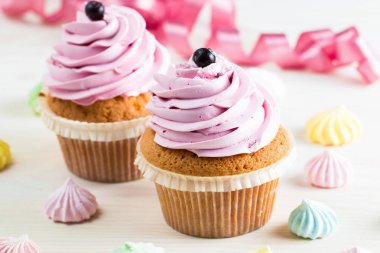 Vanilya, çilek, pembe ve beyaz krem, çikolata ve ahşap arka plan üzerinde ile cupcakes closeup. Seçici odak. Şekerli tatlı lezzetli yemekler kavramı muffin.