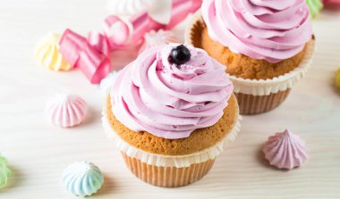 Vanilya, çilek, pembe ve beyaz krem, çikolata ve ahşap arka plan üzerinde ile cupcakes closeup. Seçici odak. Şekerli tatlı lezzetli yemekler kavramı muffin.