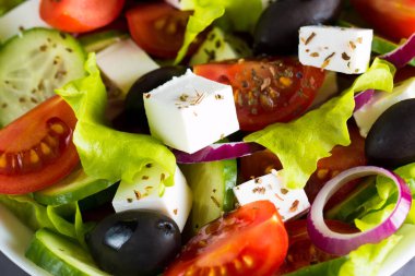 Kiraz domates, ruccola, roka, beyaz peynir, zeytin, salatalık, soğan ve baharat taze Yunan salatası yaptı. Sezar salatası ahşap arka plan üzerinde beyaz bir kase. Sağlıklı organik beslenme gıda kavramı.