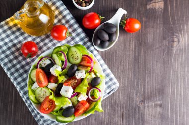 Kiraz domates, ruccola, roka, beyaz peynir, zeytin, salatalık, soğan ve baharat taze Yunan salatası yaptı. Sezar salatası ahşap arka plan üzerinde beyaz bir kase. Sağlıklı organik beslenme gıda kavramı.