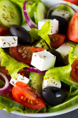 Kiraz domates, ruccola, roka, beyaz peynir, zeytin, salatalık, soğan ve baharat taze Yunan salatası yaptı. Sezar salatası ahşap arka plan üzerinde beyaz bir kase. Sağlıklı organik beslenme gıda kavramı.