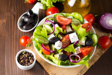 Kiraz domates, ruccola, roka, beyaz peynir, zeytin, salatalık, soğan ve baharat taze Yunan salatası yaptı. Sezar salatası ahşap arka plan üzerinde beyaz bir kase. Sağlıklı organik beslenme gıda kavramı.