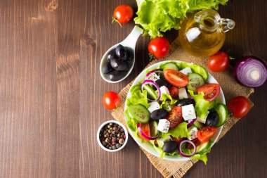 Kiraz domates, ruccola, roka, beyaz peynir, zeytin, salatalık, soğan ve baharat taze Yunan salatası yaptı. Sezar salatası ahşap arka plan üzerinde beyaz bir kase. Sağlıklı organik beslenme gıda kavramı.