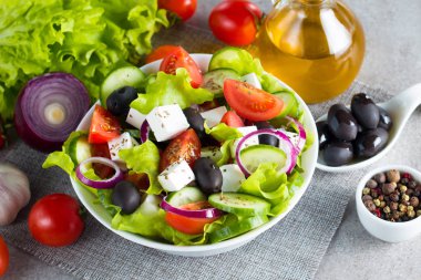 Kiraz domates, ruccola, roka, beyaz peynir, zeytin, salatalık, soğan ve baharat taze Yunan salatası yaptı. Sezar salatası ahşap arka plan üzerinde beyaz bir kase. Sağlıklı organik beslenme gıda kavramı.