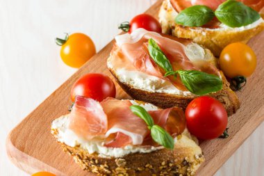 İtalyan domates, jambon, jamon, jambon ve peynir bruschetta. Tapas, antipasti Doğranmış sebzeler, otlar ve petrol ızgara ciabatta ve baget ekmek.