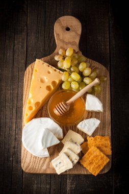 Kayrak kurulu çeşitli peynir ve kırmızı gül şarap ile. Brie. Camembert. Gouda, Masdaam, rokfor, kaşar ve üzüm fındık, tatlım, kraker, ahşap üzerine peynir mavi. İtalyan, Fransız peynir.