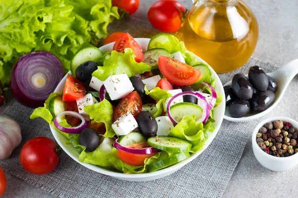 Kiraz domates, ruccola, roka, beyaz peynir, zeytin, salatalık, soğan ve baharat taze Yunan salatası yaptı. Sezar salatası ahşap arka plan üzerinde beyaz bir kase. Sağlıklı organik beslenme gıda kavramı.