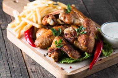 Yakın çekim fotoğraf Barbekü tavuk kanatlı patates ve bira. Barbekü soslar, ketçap, mayonez etli. Hızlı ve abur cubur kavramı. 