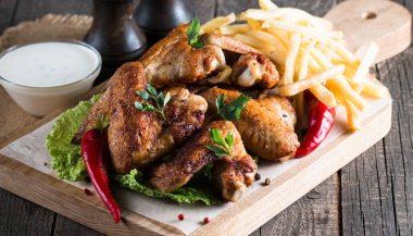 Yakın çekim fotoğraf Barbekü tavuk kanatlı patates ve bira. Barbekü soslar, ketçap, mayonez etli. Hızlı ve abur cubur kavramı. 