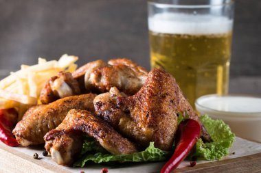 Yakın çekim fotoğraf Barbekü tavuk kanatlı patates ve bira. Barbekü soslar, ketçap, mayonez etli. Hızlı ve abur cubur kavramı. 