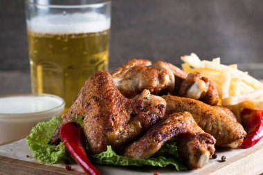 Yakın çekim fotoğraf Barbekü tavuk kanatlı patates ve bira. Barbekü soslar, ketçap, mayonez etli. Hızlı ve abur cubur kavramı. 