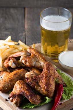 Yakın çekim fotoğraf Barbekü tavuk kanatlı patates ve bira. Barbekü soslar, ketçap, mayonez etli. Hızlı ve abur cubur kavramı. 