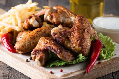 Yakın çekim fotoğraf Barbekü tavuk kanatlı patates ve bira. Barbekü soslar, ketçap, mayonez etli. Hızlı ve abur cubur kavramı. 