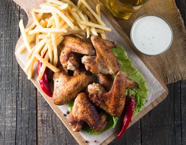 Yakın çekim fotoğraf Barbekü tavuk kanatlı patates ve bira. Barbekü soslar, ketçap, mayonez etli. Hızlı ve abur cubur kavramı. 