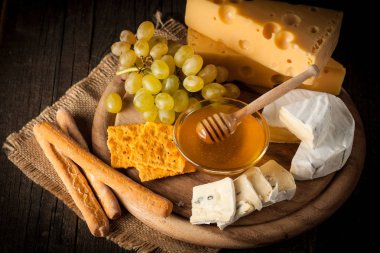 Kayrak kurulu çeşitli peynir ve kırmızı gül şarap ile. Brie. Camembert. Gouda, Masdaam, rokfor, kaşar ve üzüm fındık, tatlım, kraker, ahşap üzerine peynir mavi. İtalyan, Fransız peynir.