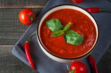 Ekşi krema sos, peynir, fesleğen ve ahşap zemin üzerine kırmızı biber biber domates çorbası. Sağlıklı, vegan ve diyet öğle ve akşam yemeği kavramı.