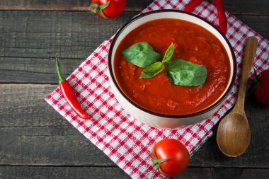 Ekşi krema sos, peynir, fesleğen ve ahşap zemin üzerine kırmızı biber biber domates çorbası. Sağlıklı, vegan ve diyet öğle ve akşam yemeği kavramı.