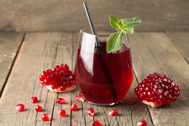 Bir bardak nar suyu ve ahşap masada taze nar meyveleri. Vitamin ve mineraller. Sağlıklı içki konsepti.