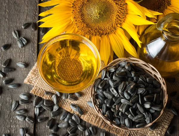 Sunflower oil and sunflower seeds in small sack on traditional rustic wooden background. Organic and eco food concept. Healthy food and fats.