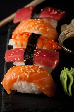 Sashimi ve suşi rulo üzerinde bir taş slatter. Suşi somon, karides, soya sosu, wasabi ve zencefil ile ayarla. Geleneksel Japon mutfağı.