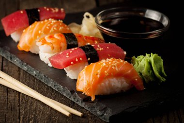 Sashimi ve suşi rulo üzerinde bir taş slatter. Suşi somon, karides, soya sosu, wasabi ve zencefil ile ayarla. Geleneksel Japon mutfağı.